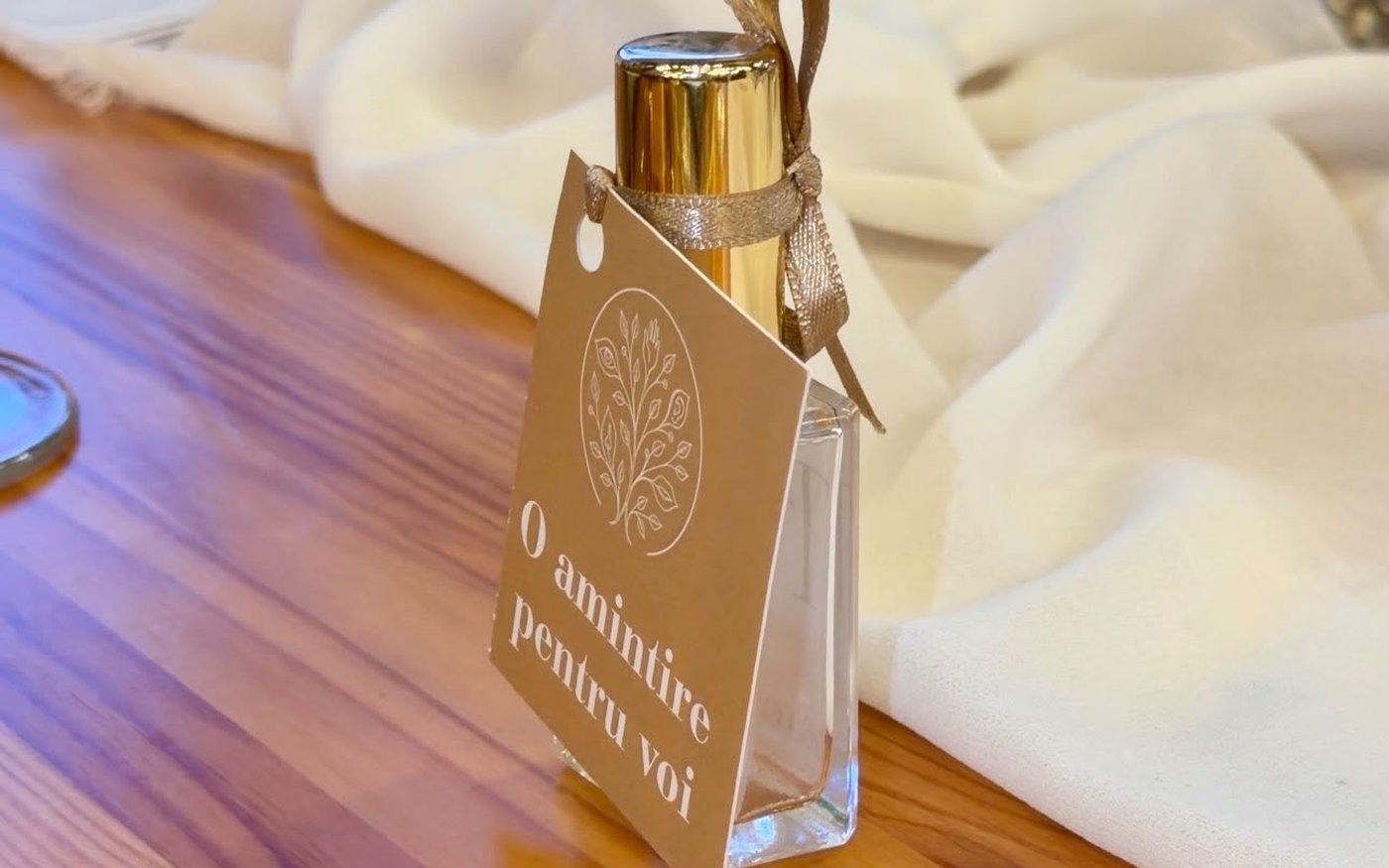 Sticluța de parfum cu cartonașul „O amintire pentru voi”, așezată la masa invitaților