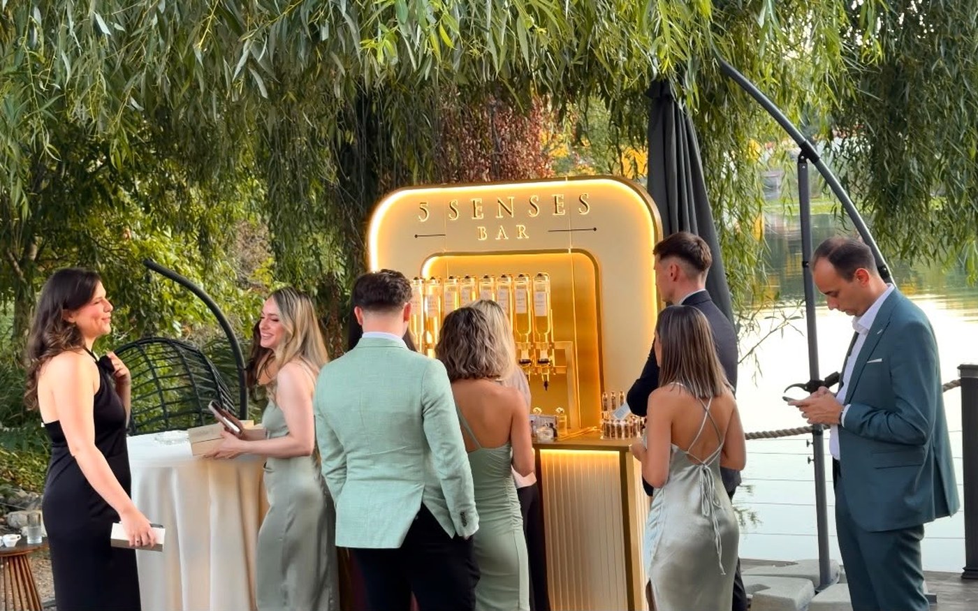 Invitați adunați în jurul standului 5 Senses Bar, la un eveniment privat în aer liber